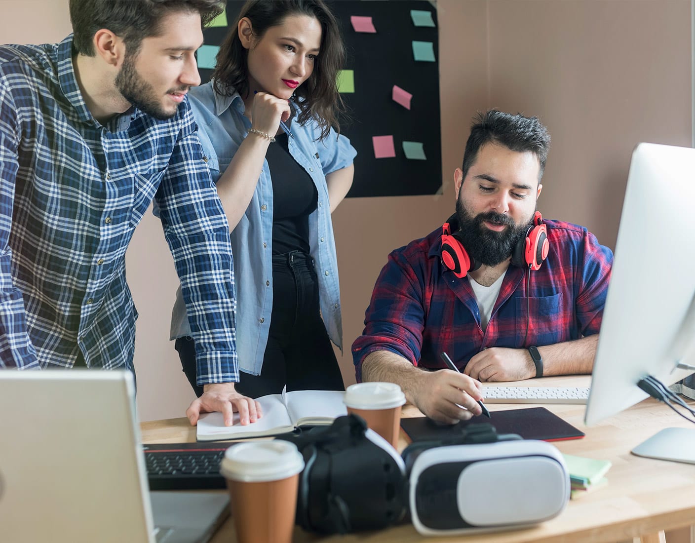 A team of three people working together at a computer in an office environment.